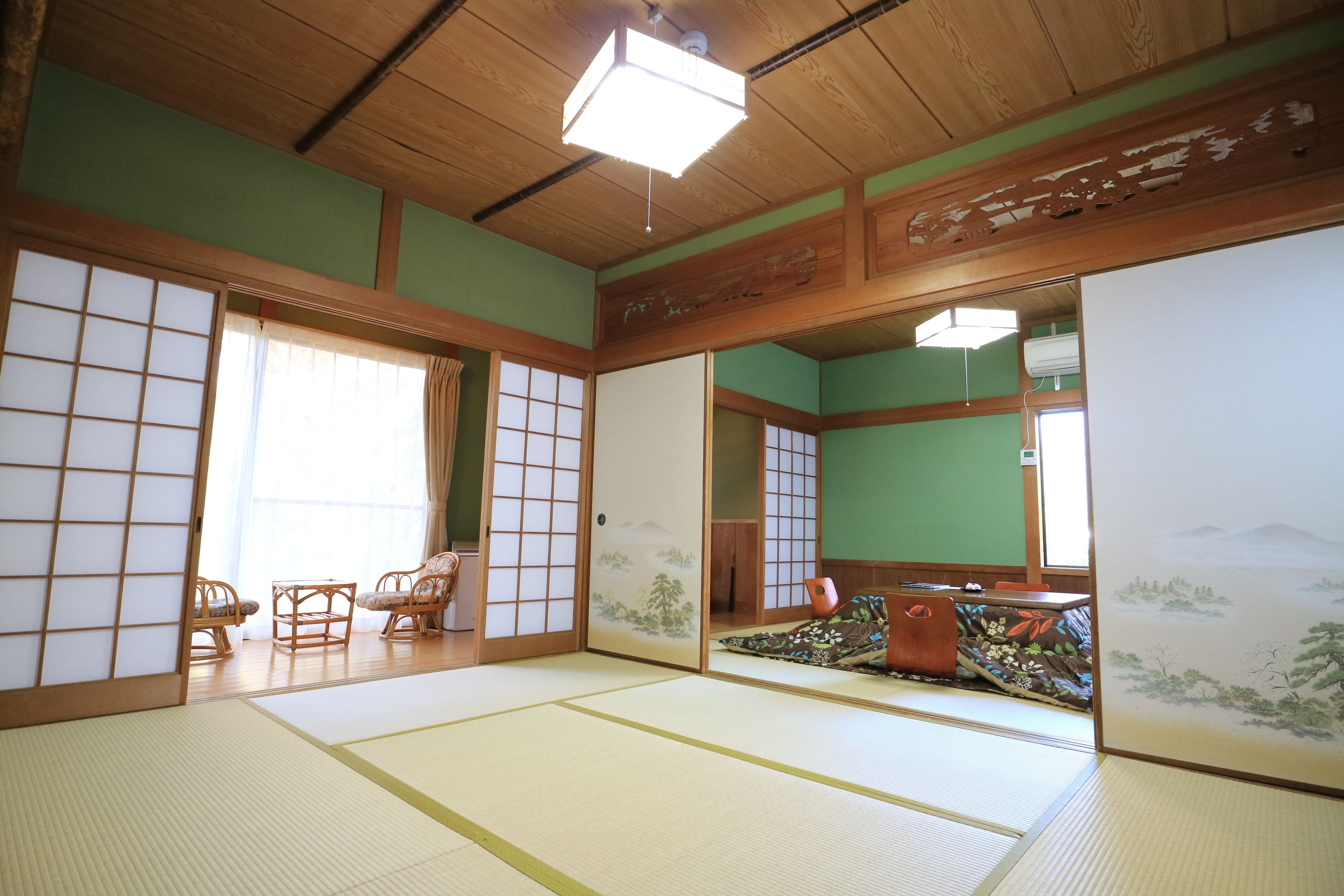 Una habitación japonesa tradicional con suelo de tatami, puertas correderas y vistas a un paisaje montañoso.