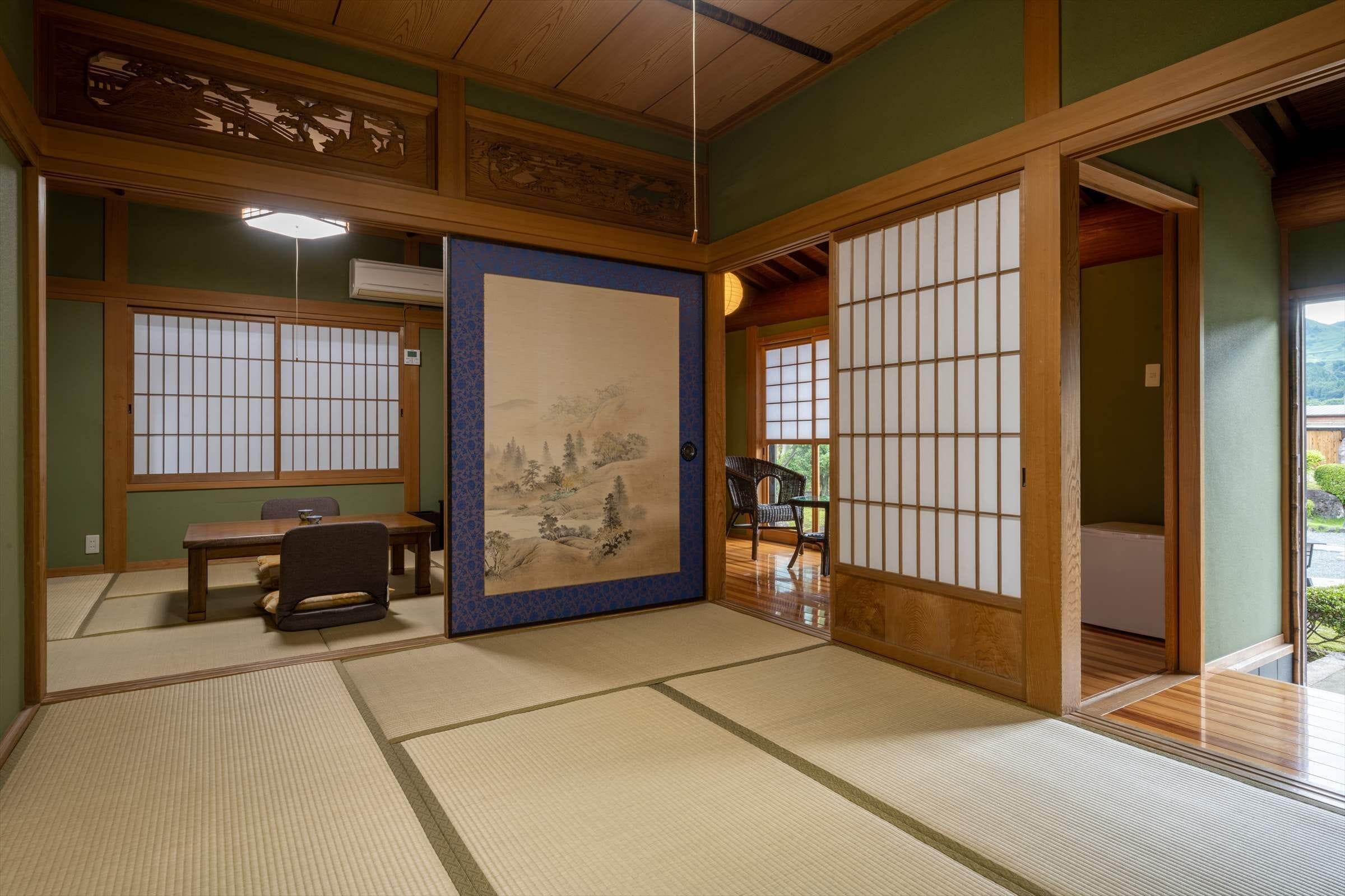 Una habitación japonesa tradicional con suelo de tatami, puerta corredera shoji, una mesa de tatami y vistas al exterior.