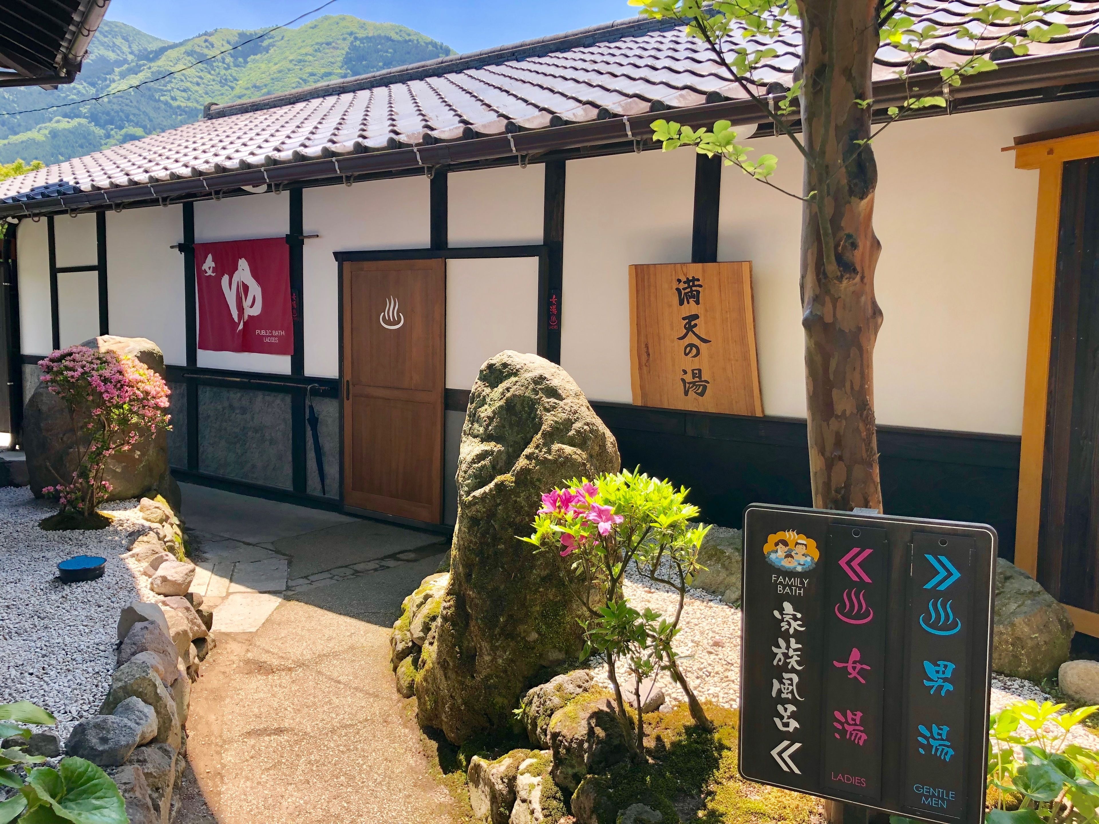 A traditional Japanese building with a tiled roof, a wooden door, and a sign indicating a family bath.