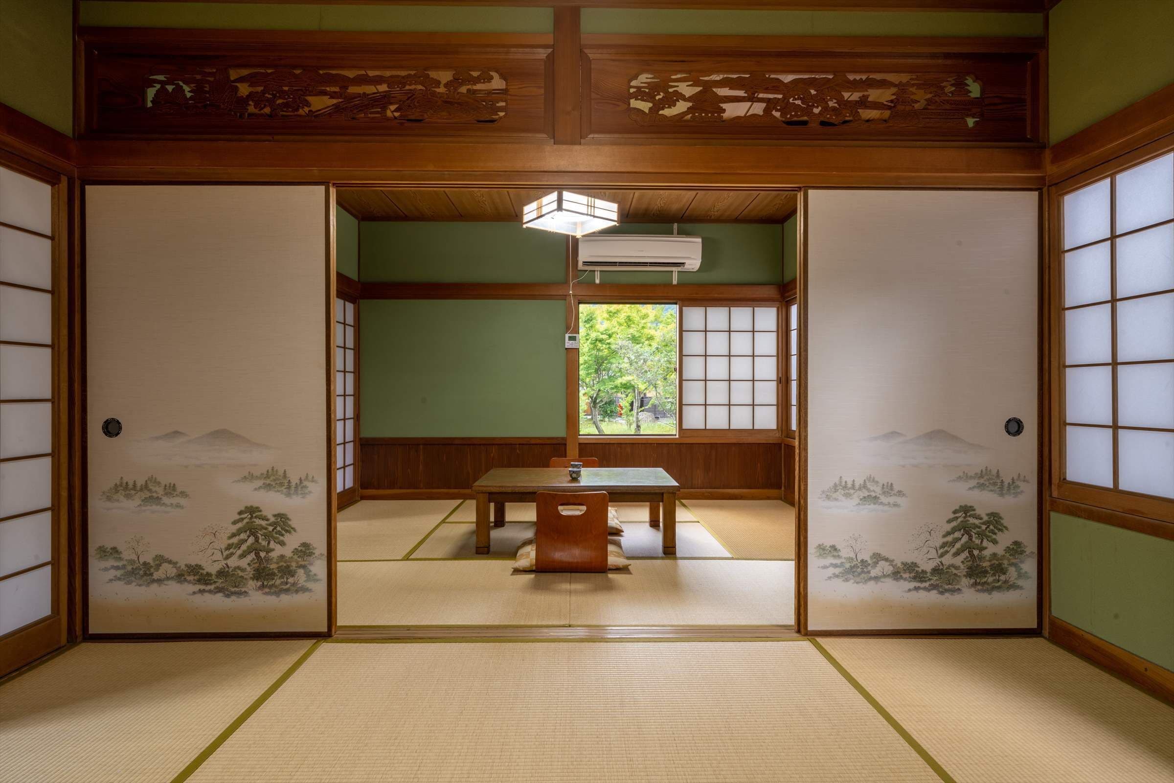A traditional Japanese room with tatami flooring, a low table with a cushion, and shoji screens.