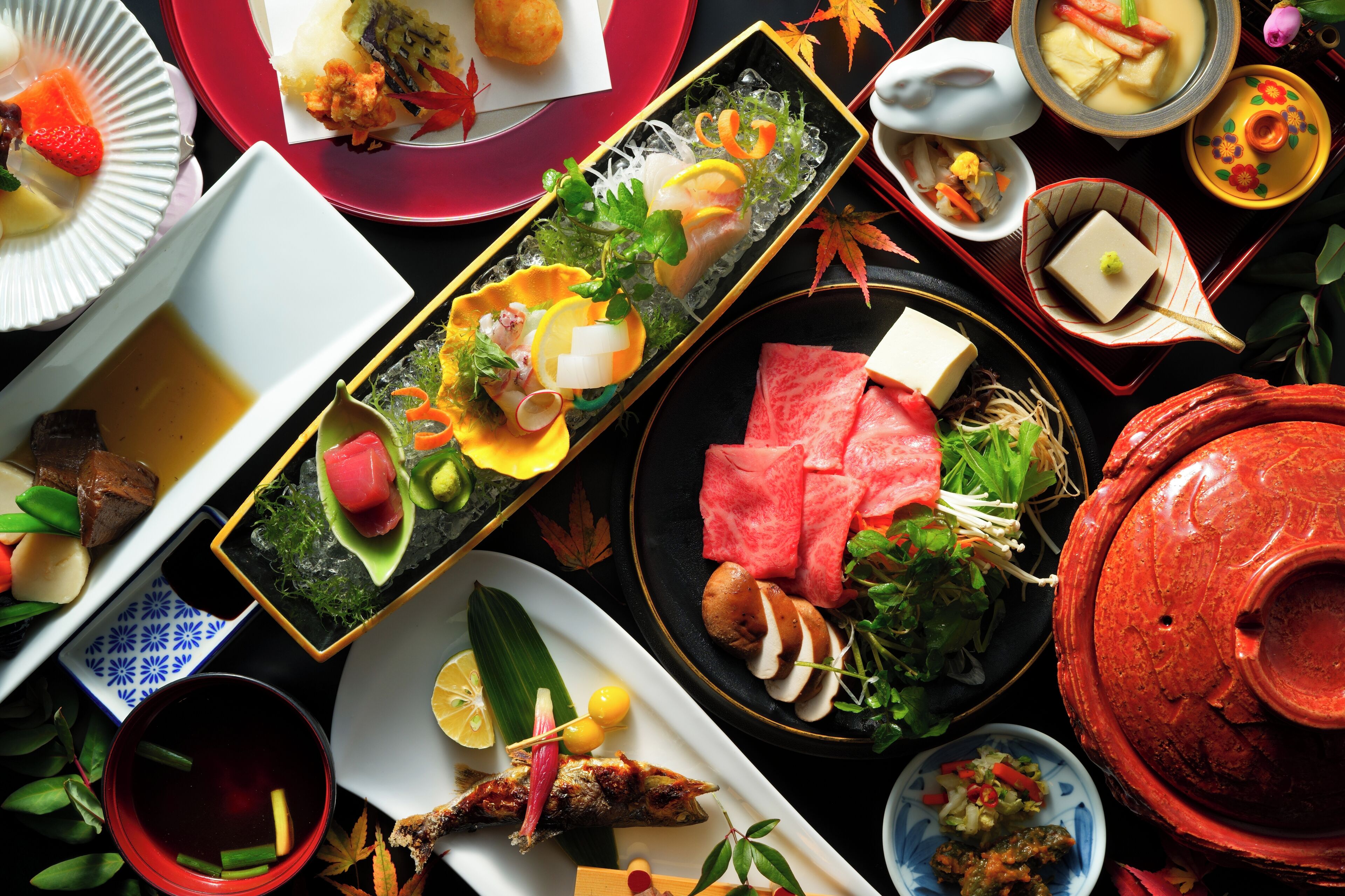 A variety of dishes on a table, including sushi, sashimi, and other Asian cuisine.