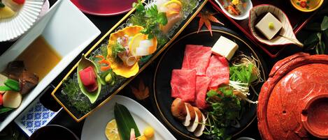 A variety of dishes on a table, including sushi, sashimi, and other Asian cuisine.