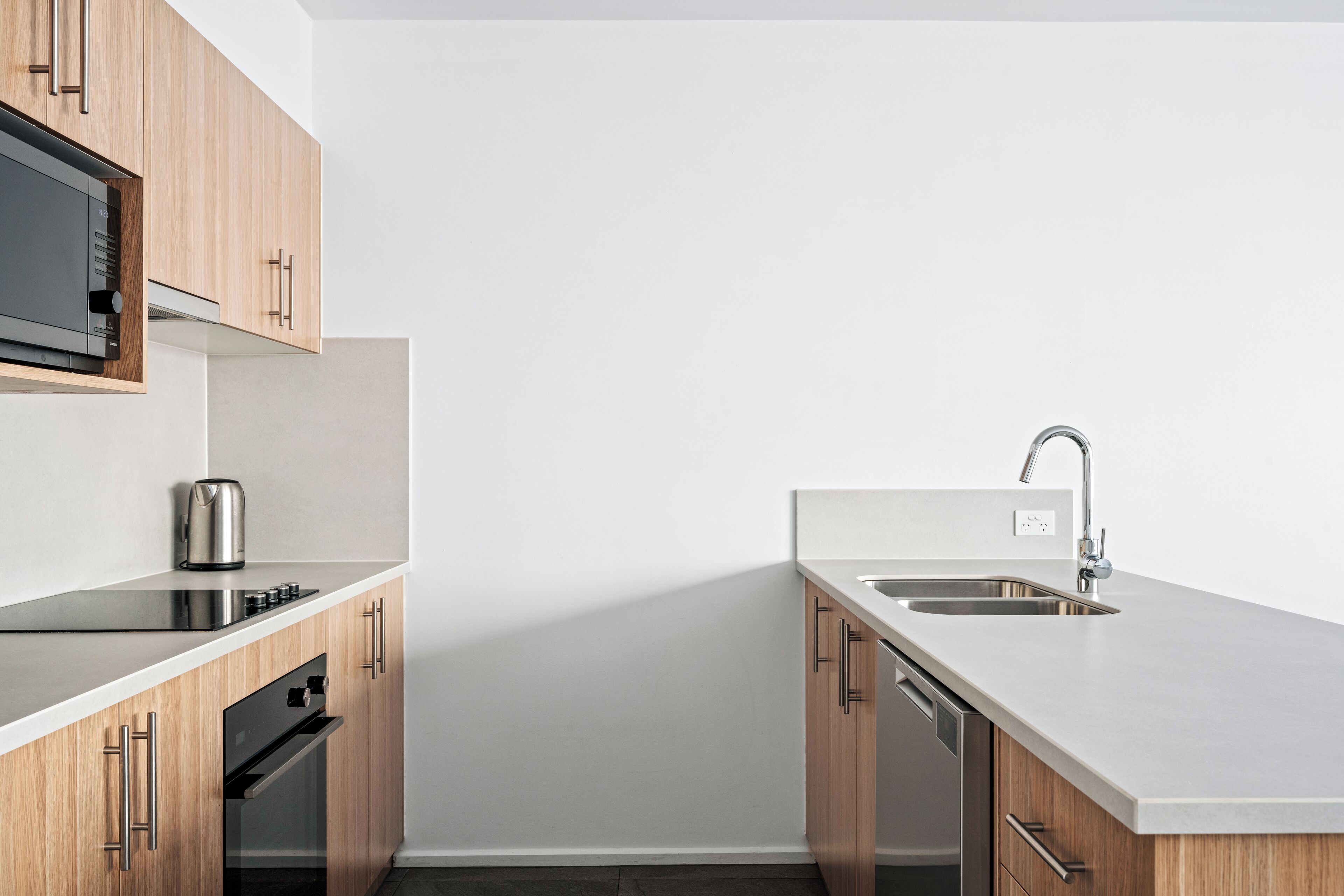 A modern kitchen with wooden cabinets, a stainless steel sink, and a built-in microwave.