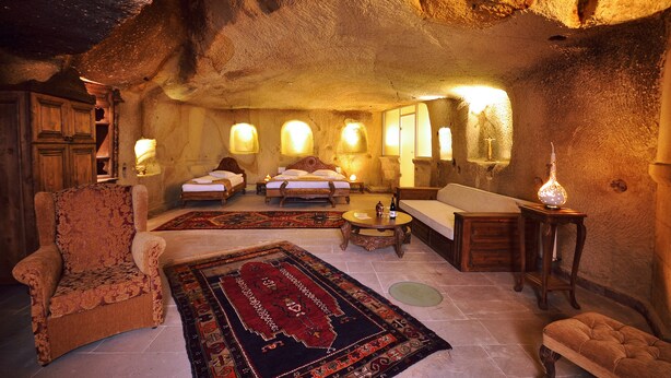 A cave-like interior with a sofa, armchair, and a large rug. - Has Cave Konak (Ürgüp)