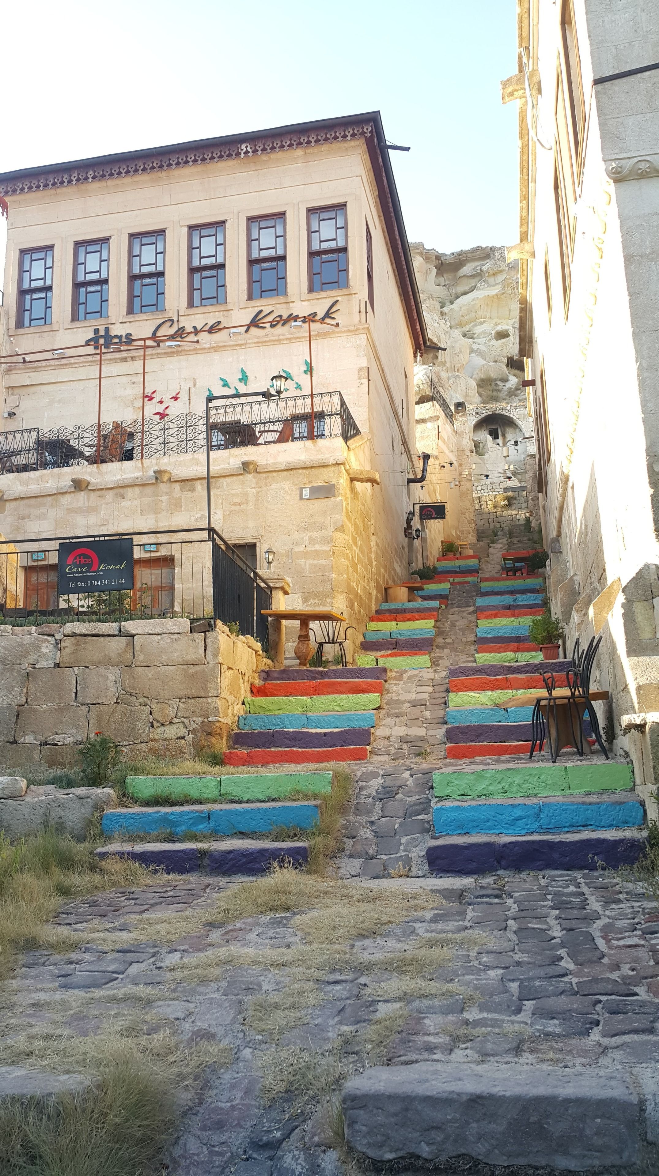 A building with a sign reading "Has Cave Konak" and a staircase with colorful steps.