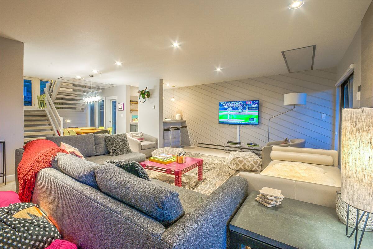 Een moderne woonkamer met een trap, een flatscreen televisie en diverse zitmogelijkheden.