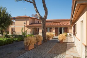 A building with a tiled roof, a paved walkway, and potted plants. - La Residenza del Golfo (Scarlino)