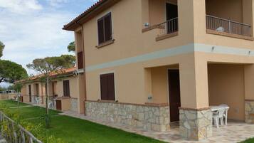 A two-story building with stone accents, a balcony, and a small outdoor seating area.