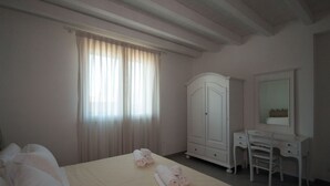 A hotel room with a bed, a wardrobe, a vanity with a mirror, and a window with curtains. - La Residenza del Golfo (Scarlino)