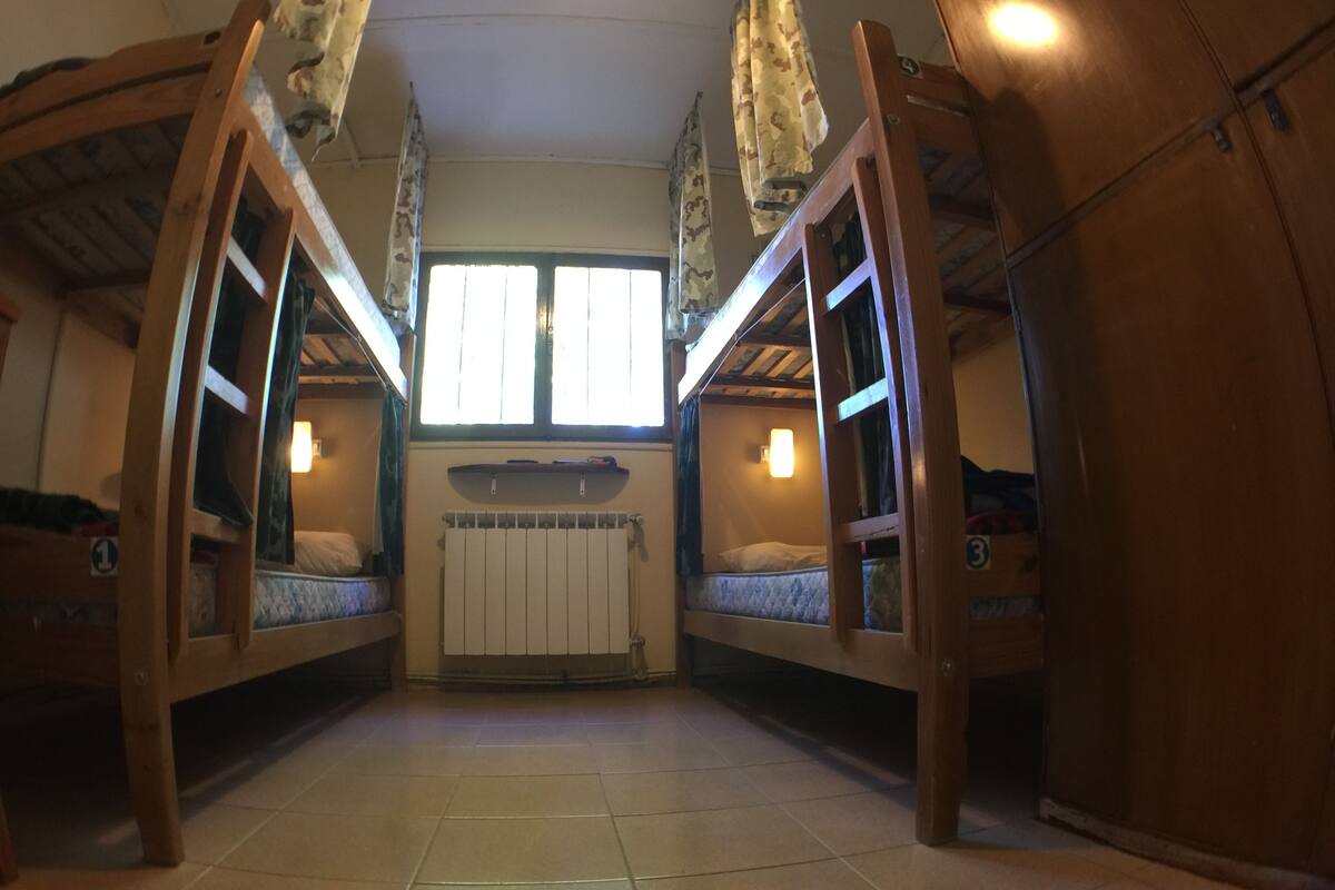 Une chambre avec des lits superposés, un radiateur et une fenêtre avec des rideaux.