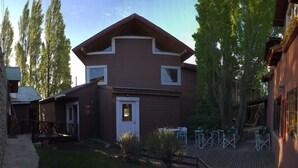 A rustic cabin with a sloped roof, a front door, and a small porch with outdoor seating. - Hostel del Glaciar Pioneros (El Calafate)