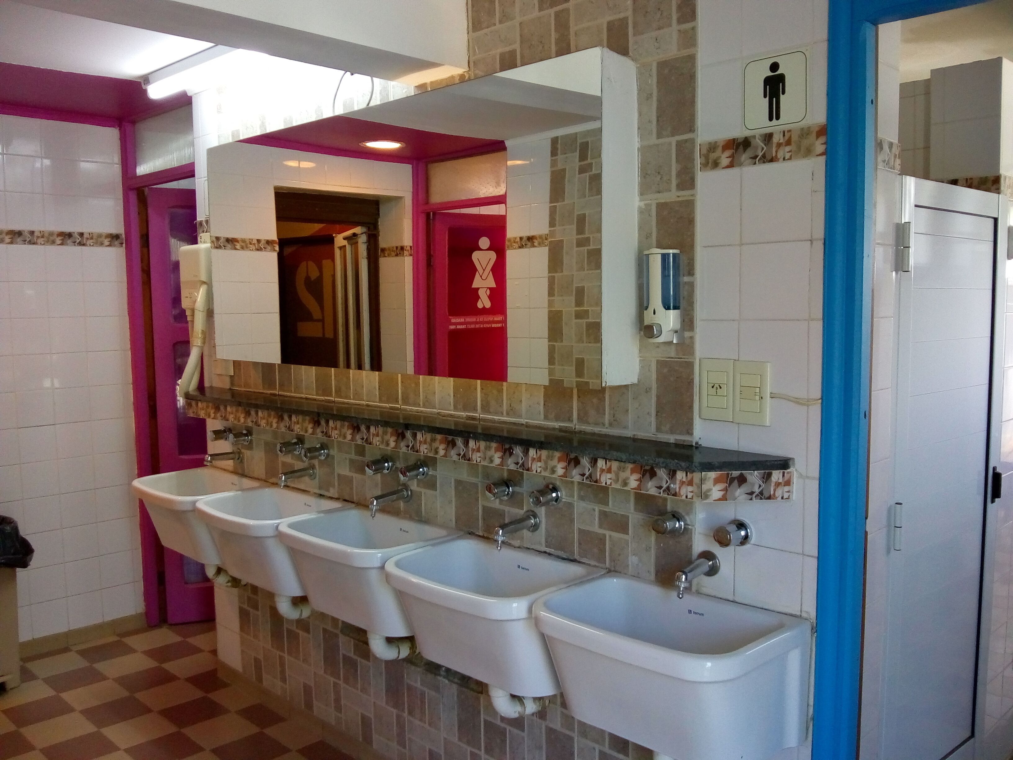 A public restroom with four sinks, a large mirror, and a red door.