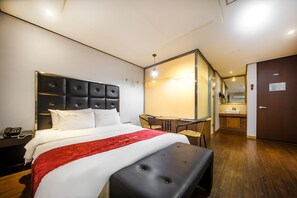 Habitación de hotel con cama, escritorio y una pequeña kitchenette.