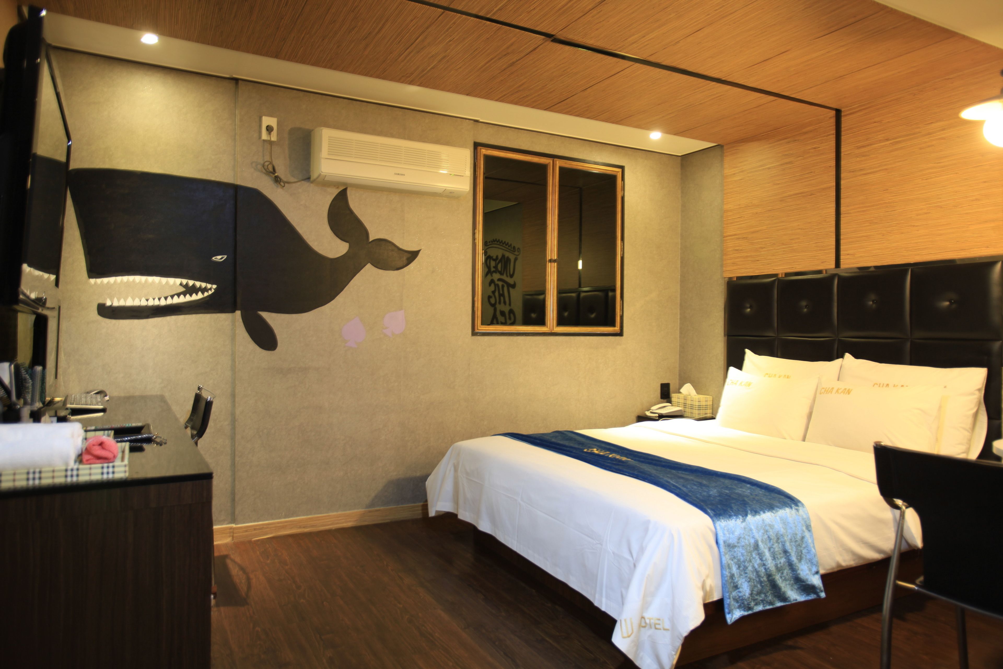 A hotel room with a bed, a desk, and a wall with a whale mural.