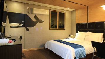 A hotel room with a bed, a desk, and a wall with a whale mural.