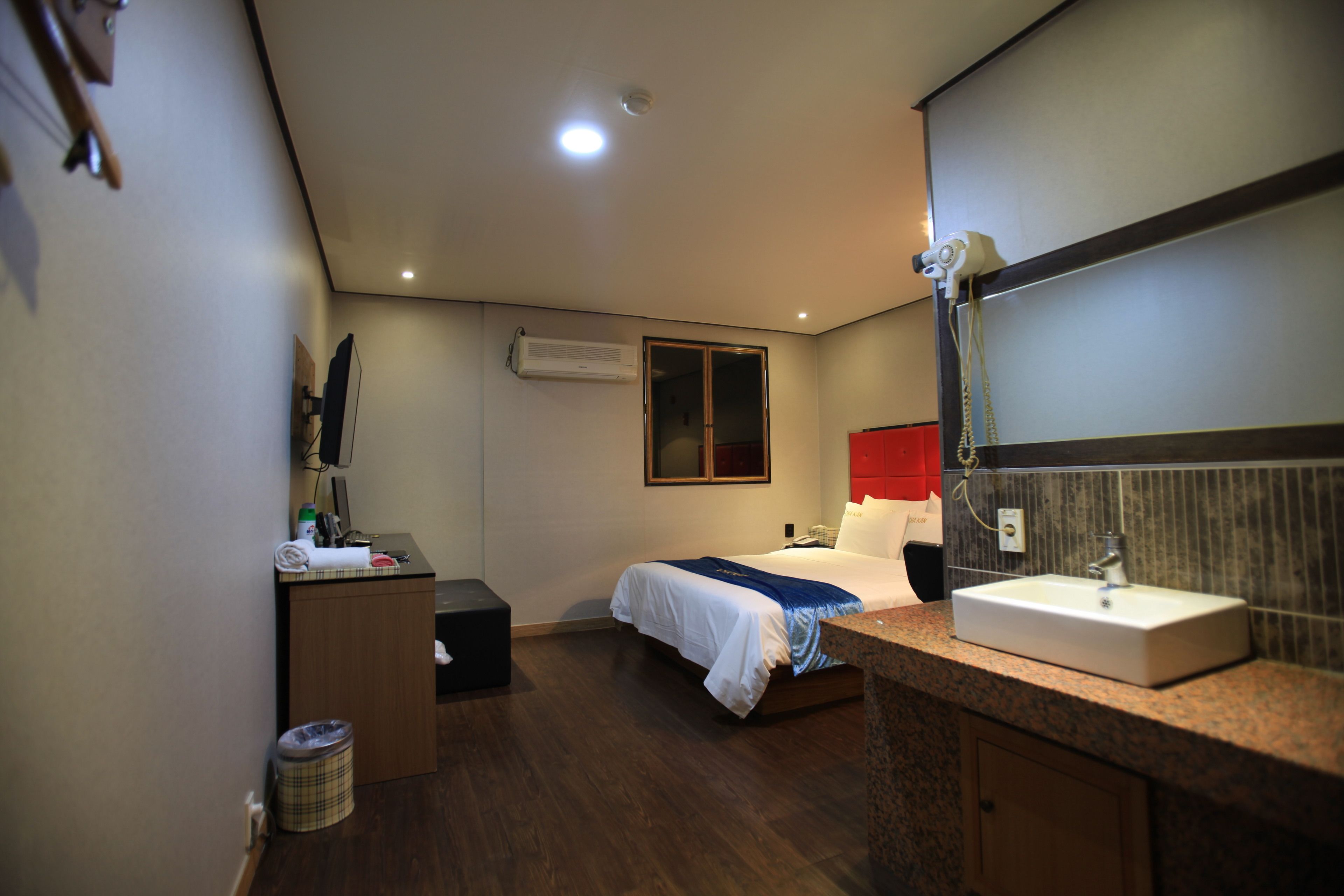 Una habitación de hotel con una cama, un escritorio, un lavabo y un espejo.
