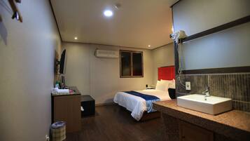Una habitación de hotel con una cama, un escritorio, un lavabo y un espejo.