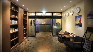 A lobby with a reception desk, a bookshelf, a clock, and a poster on the wall.