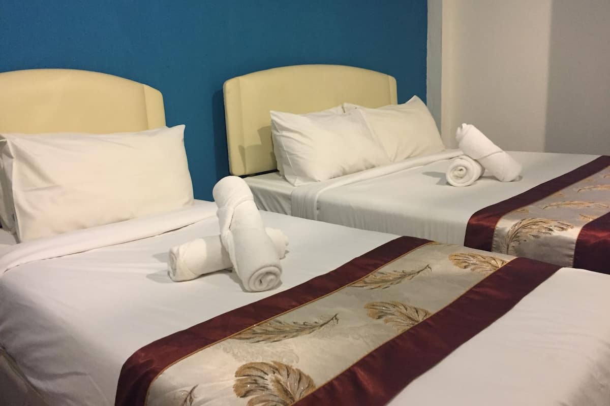 Two single beds with white linens and pillows, a blue wall, and a red decorative border on the beds.