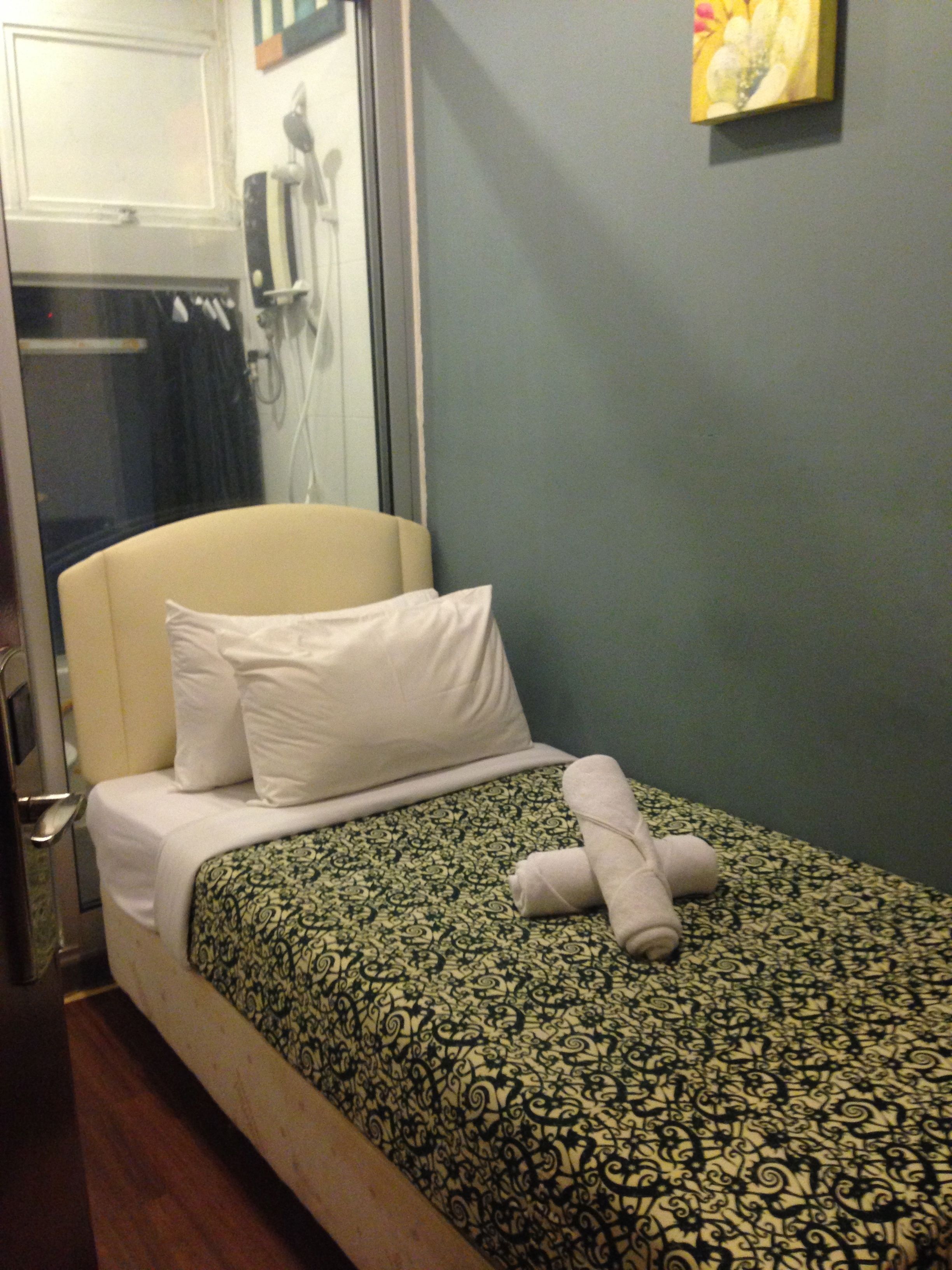 A hotel room with a bed, a bedside table, and a wall with a painting.