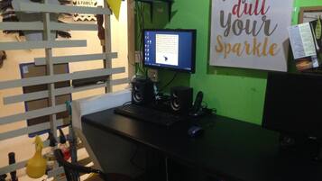 A home office setup with a desk, computer, and speakers. A sign on the wall reads "Don't let anyone dull your sparkle."