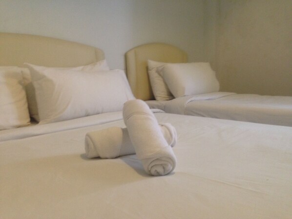 A hotel room with two beds, each with white linens and pillows.