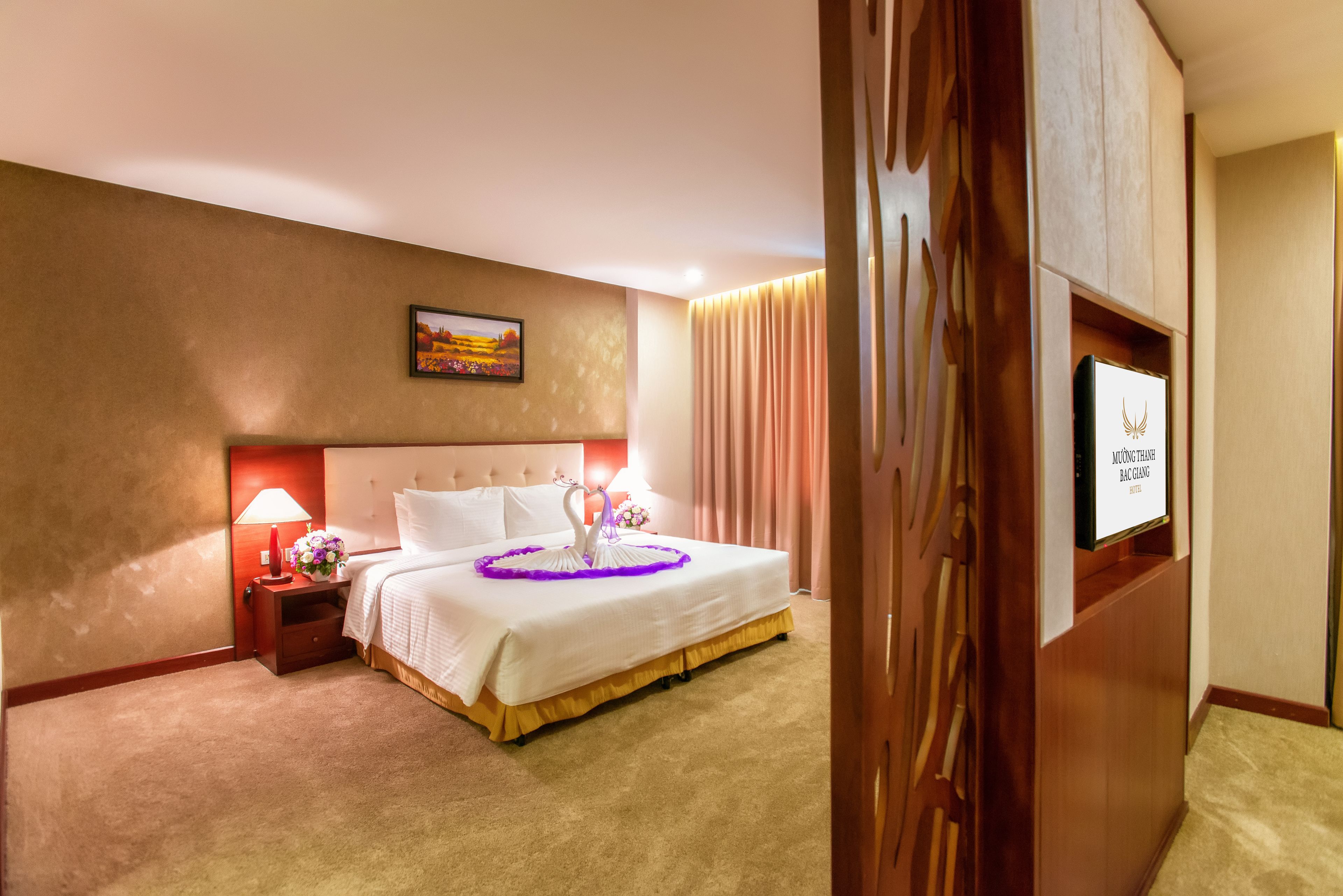 A hotel room with a bed, a nightstand, a lamp, a picture on the wall, and a sign on the door.