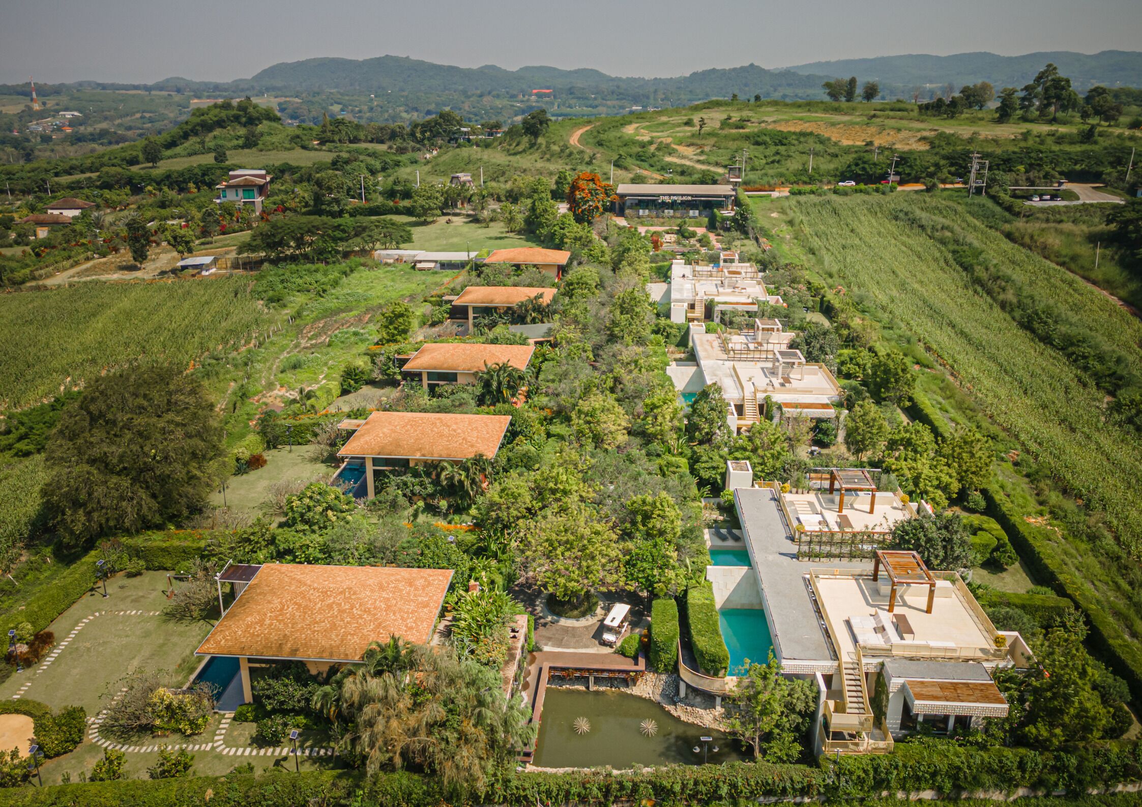 An aerial view of a resort with multiple buildings, a swimming pool, and lush greenery.