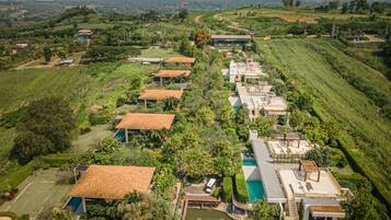 An aerial view of a resort with multiple buildings, a swimming pool, and lush greenery.