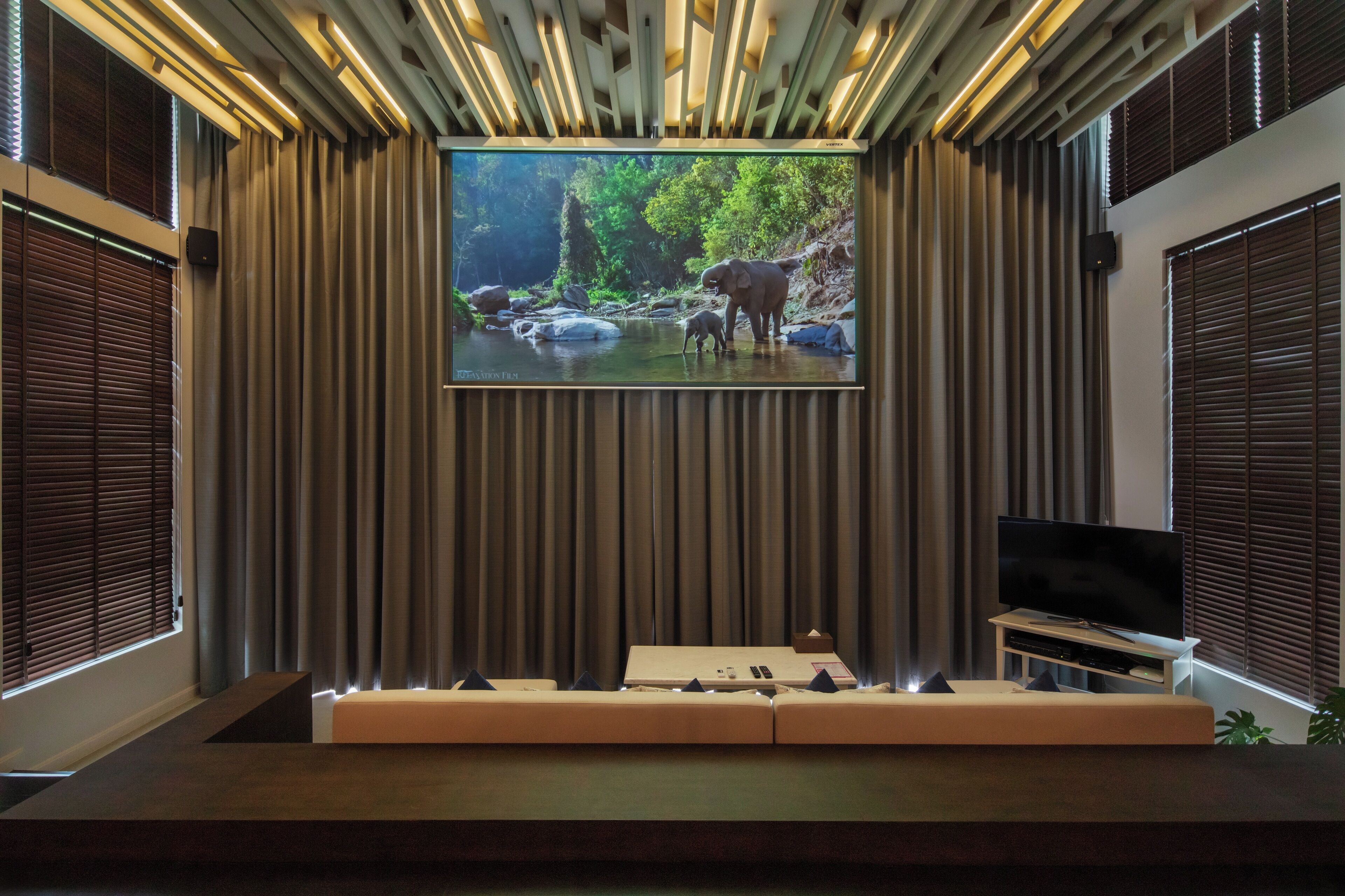 A modern living room with a large flat-screen TV mounted on a wall, a sofa, and a small entertainment unit.