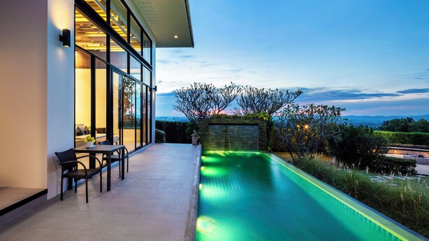 A modern house with a swimming pool, outdoor seating, and a view of the landscape. - The Private Pool Villas at Civilai Hill Khao Yai (Pak Chong)