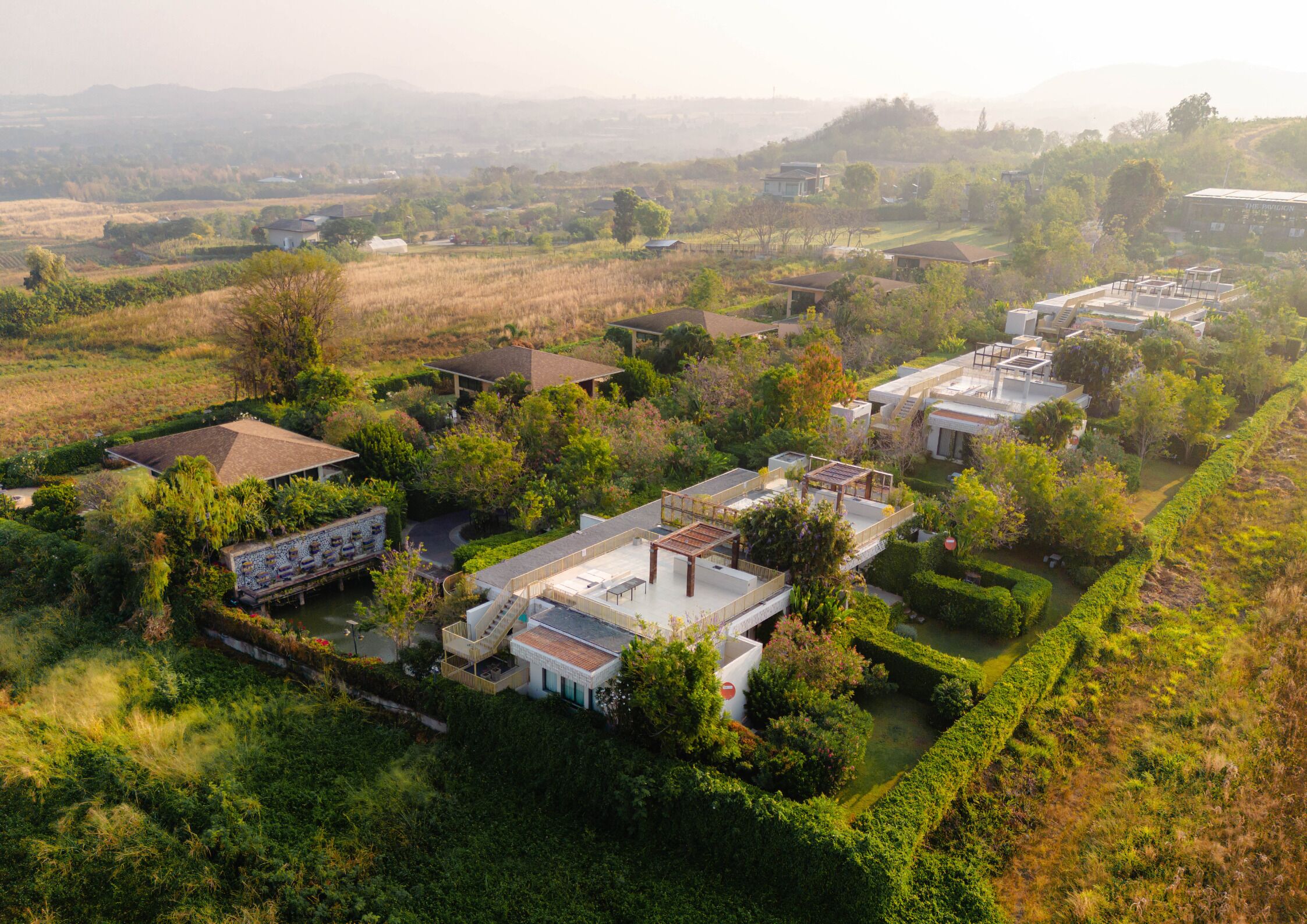 An aerial view of a residential area with houses surrounded by lush greenery and a river.