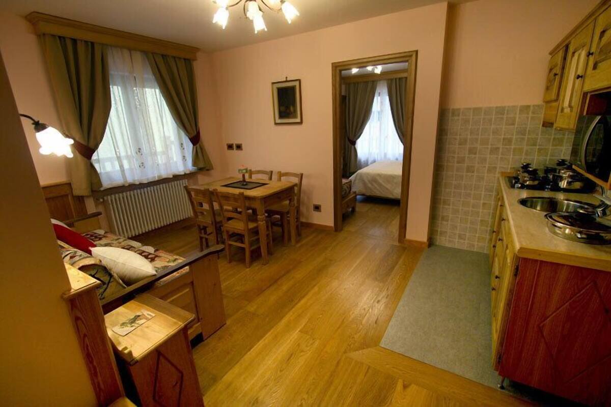 A compact room with a bed, a small dining table, and a kitchenette.