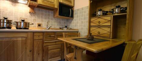 A kitchen with wooden cabinets, a microwave, and various pots and pans.