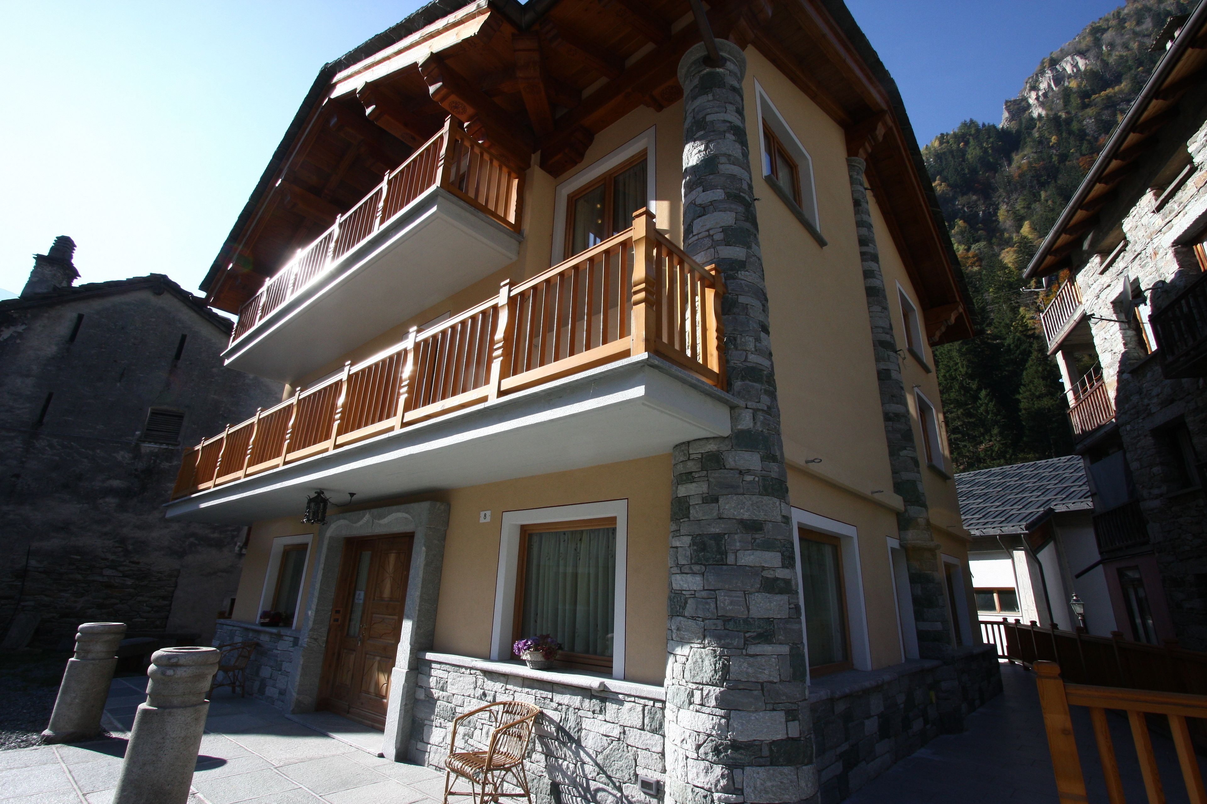 Un bâtiment à deux étages doté d’un balcon, de piliers en pierre et ayant une chaîne de montagnes en toile de fond.