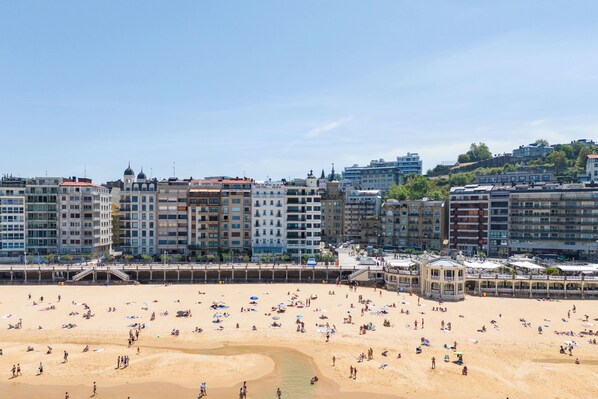 Una playa con gente y edificios al fondo.