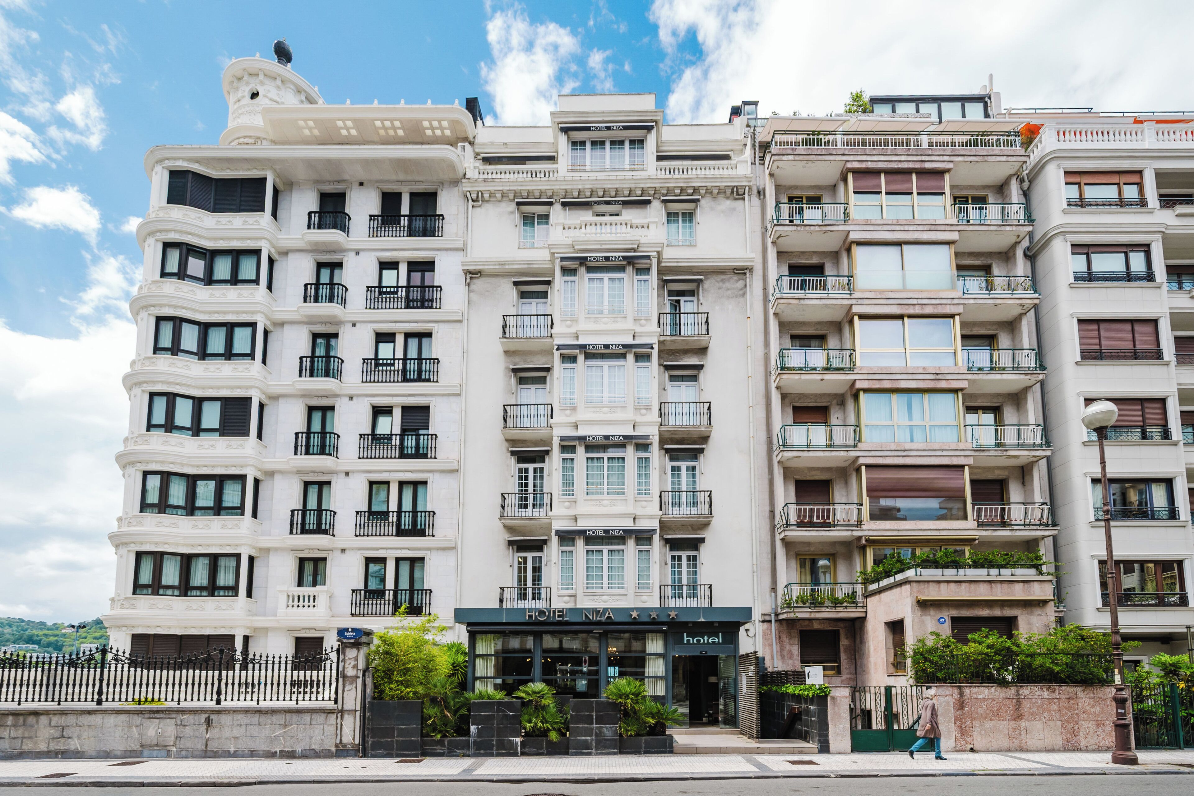 Un hotel de varios pisos con balcones, una entrada principal y cielo despejado.