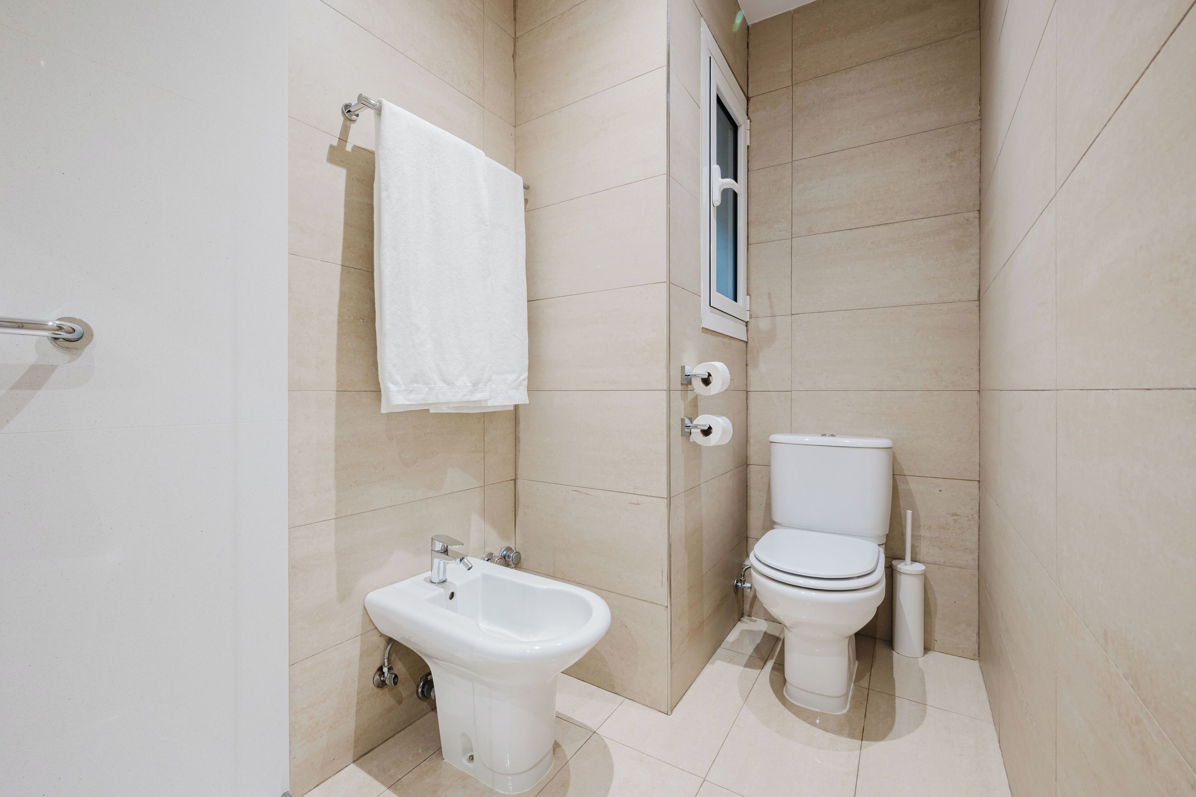 Une salle de bain moderne équipée d’un bidet, de toilettes et d’un porte-serviettes.