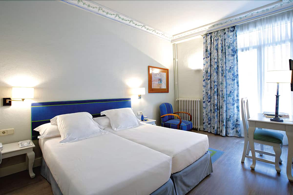 Escritorio, cortinas opacas, tabla de planchar con plancha