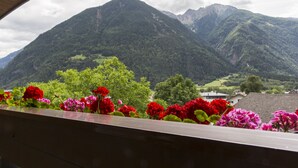A mountain view with a balcony adorned with red and pink flowers. - Hotel Mühlener Hof (Campo Tures)