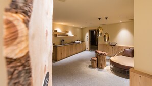 A modern interior with a wooden reception desk, a round bed, and a small seating area with stools. - Hotel Mühlener Hof (Campo Tures)