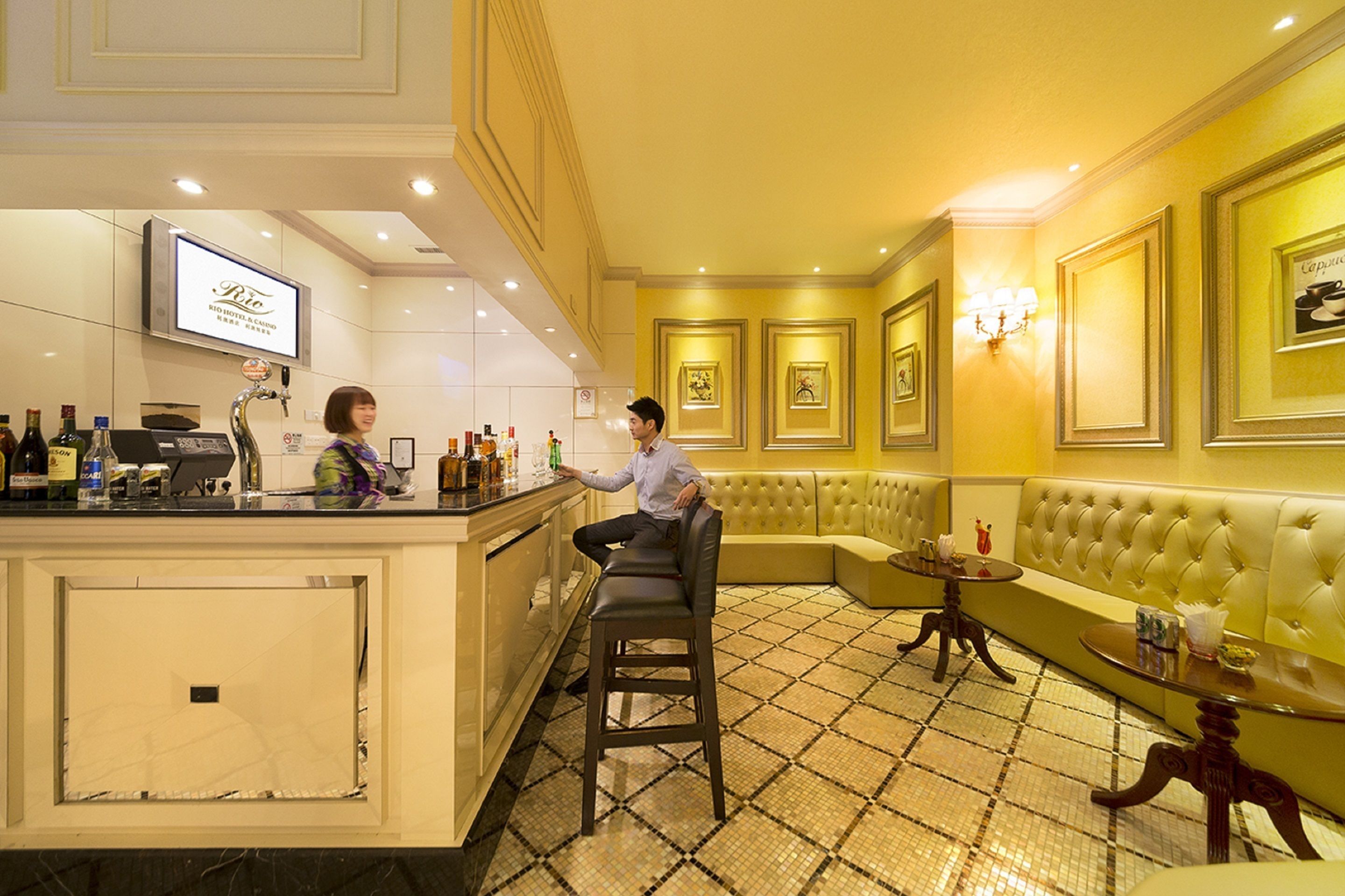 Un espace bar comprenant un comptoir, des tabourets et un coin salon avec un canapé et une table.