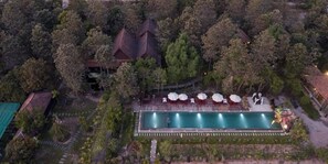 An aerial view of a resort with a swimming pool, surrounded by trees and a few buildings. - Bong Thom Home Stay (Banteay Srei)