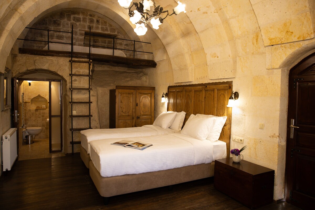Un dormitorio con una cama grande, cabecera de madera, una escalera y una puerta de madera.