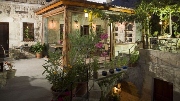 A stone building with a wooden balcony, potted plants, and outdoor seating.