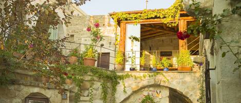 A courtyard with stone walls, potted plants, and a dog lying on the ground.
