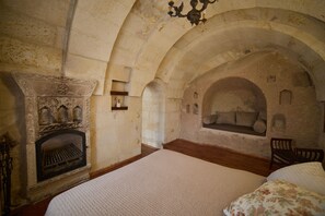 Een kamer met een open haard, een bed en een bank onder een gewelfde plafond.