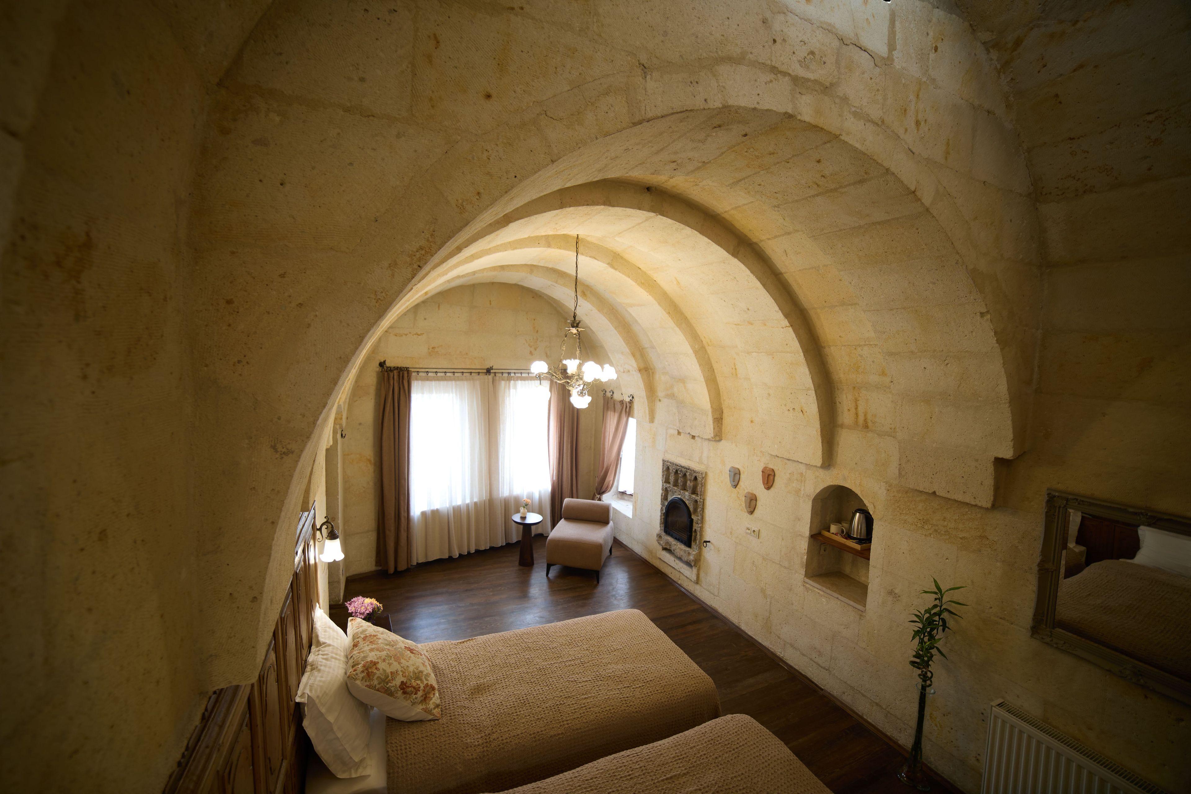 Una habitación con techo abovedado, chimenea, sofá y candelabro.