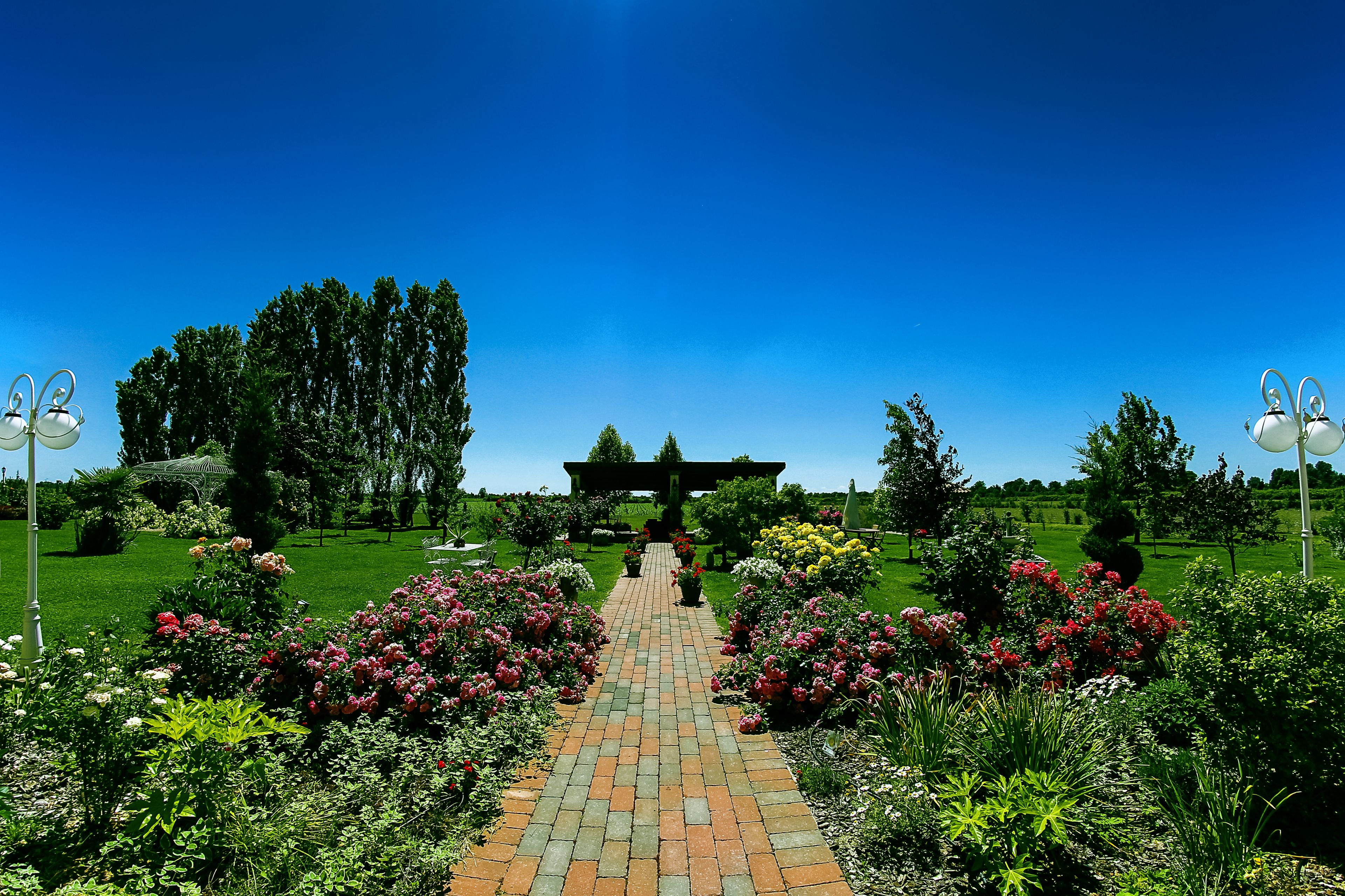 A garden pathway leading to a gazebo surrounded by lush greenery and flowering plants.