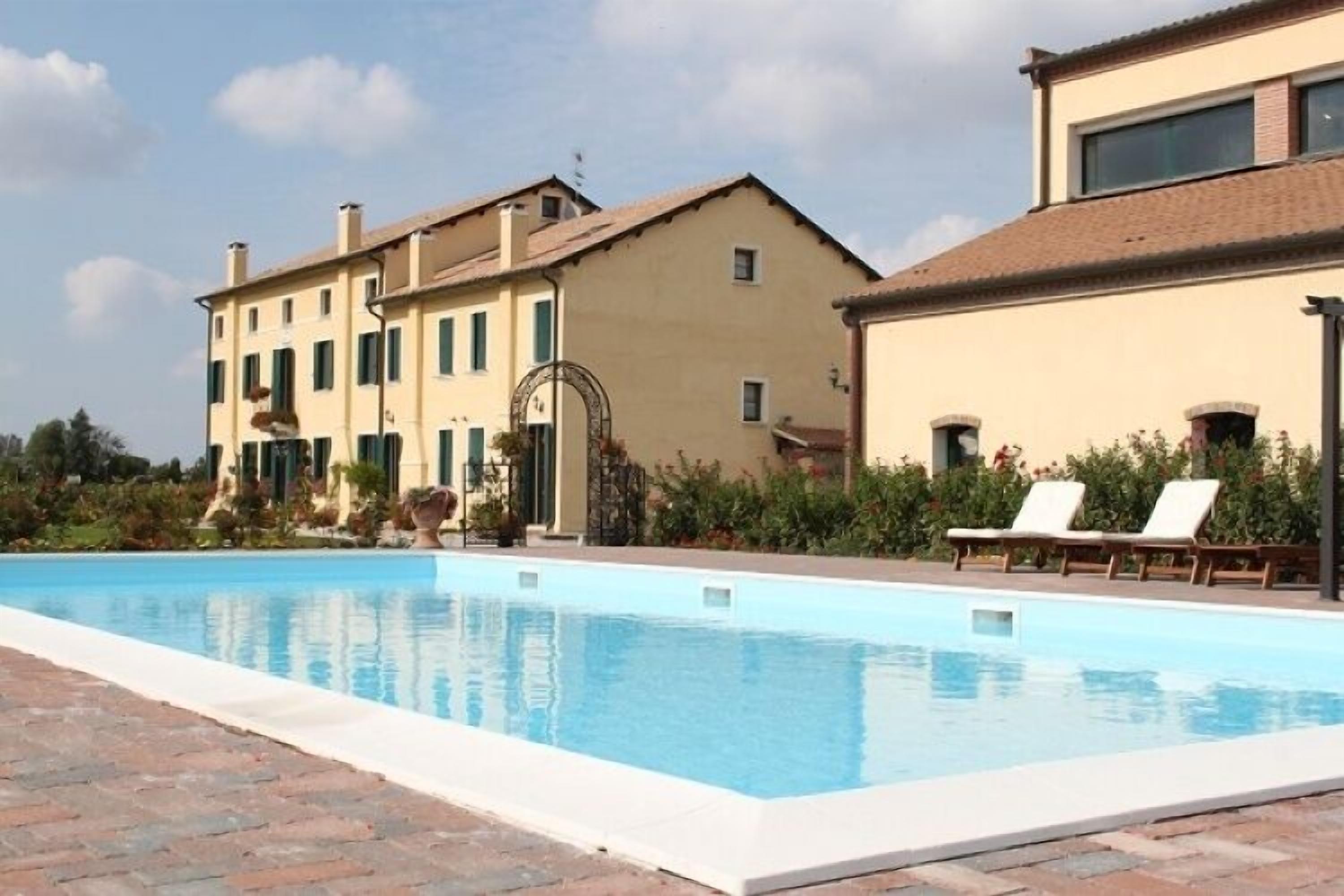 A swimming pool with lounge chairs, a building with a beige facade, and a clear sky.